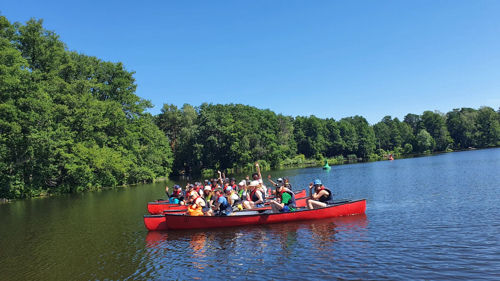 Volle Boote unterwegs am Waldufer
