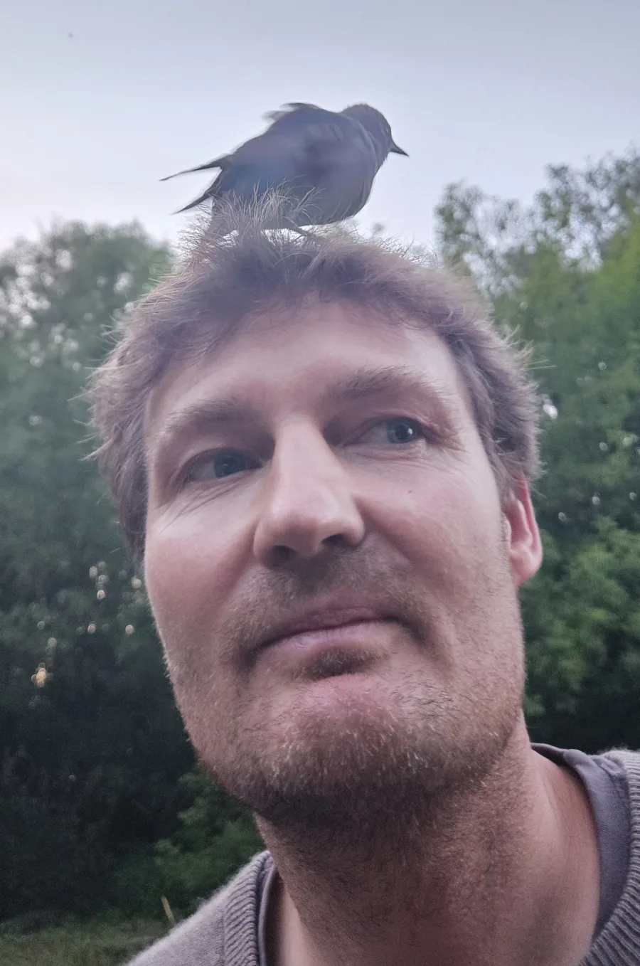 Selfie von Christian mit einem jungen Vogel auf dem Kopf